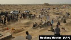 Mourners gather next to graves of victims of the October 8 suicide bomb attack on worshippers at a Shi'ite mosque in Kunduz, in which at least 55 people died. The attack was claimed by the Islamic State-Khorasan.