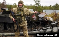 A Ukrainian soldier holds up the emblem of an elite unit of Russia's armed forces near destroyed Russian tanks in the village of Dmytrivka, close to Kyiv, on April 2.