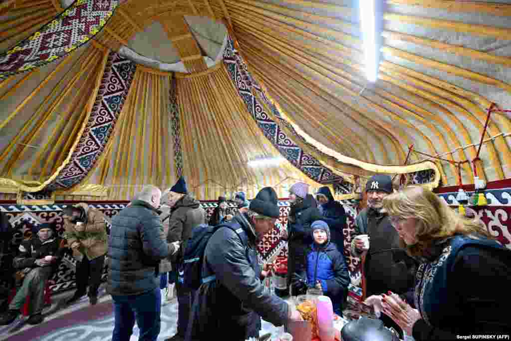 Members of the public help themselves to free baursaki, milk, tea, coffee, and cookies as they take the opportunity to warm themselves inside the unique enclosure.