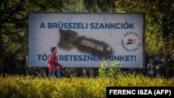 In Budapest on October 18, a man passes by a poster depicting a bomb, with the text, "We are being punished by the Brussels sanctions."