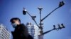 A man wearing a face mask walks past surveillance cameras following the COVID-19 outbreak in Shanghai, China, in 2021.