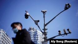 A man wearing a face mask walks past surveillance cameras following the COVID-19 outbreak in Shanghai, China, in 2021.