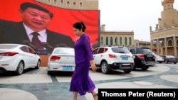 An ethnic Uyghur woman walks in front of a giant screen showing Chinese President Xi Jinping in the main square in the city of Kashgar in the Xinjiang Uyghur Autonomous Region. (file photo)