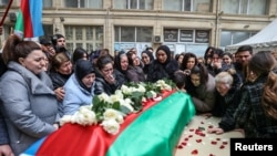 People gather around the coffin of Orkhan Askerov, a security guard at Azerbaijan's embassy in Iran who was shot dead by a gunman, during a procession in Baku on January 30.