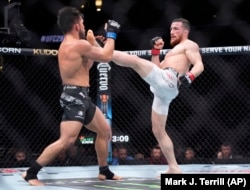 Merab Dvalishvili (right) throws a kick at Henry Cejudo during their bantamweight bout at UFC 298 in California.