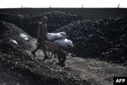 A day laborer pushes a wheelbarrow at a coal yard on the outskirts of Kabul in November 2021.