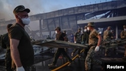 Rescue services work at the site of a shopping mall hit by a Russian missile strike in Kremenchuk on June 27.