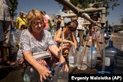 Women fill bottles with water provided by a volunteer organization in Mykolayiv.