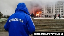 Protesters rally on January 5 outside the Almaty mayor’s office, which was on fire.