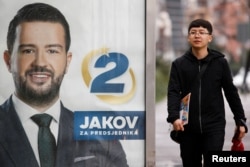 A pedestrian passes a campaign poster for Jakov Milatovic in Podgorica.