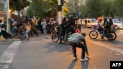 An Iranian police officer raises a baton to disperse demonstrators during a protest in Tehran on September 19 following the death in custody of 22-year-old Mahsa Amini, who was detained by the morality police three days earlier.