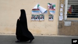 A woman walks past election campaign posters for the March 1 parliamentary election in downtown Tehran on February 22.