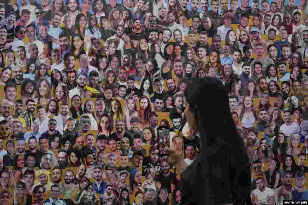 A woman walks past a mural with portraits of victims at the site of the Nova music festival on the one-year anniversary.