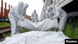 Ukrainian workers carry the bodies of Russian soldiers killed during the invasion before putting them in a refrigerated rail car in Kyiv on May 13.