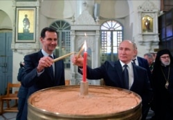 Russian President Vladimir Putin and Syrian President Bashar al-Assad light candles while visiting an Orthodox cathedral for Christmas in Damascus on January 7.