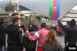 Spectators wave and shoot video as a Turkish-made T-300 Kasirga multiple-rocket-launching system passes by.