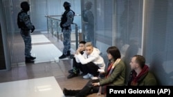 Employees of Aleksei Navalny's Anti-Corruption Foundation sit on the floor as security officers stand guard a raid on their office in Moscow in November 2020.