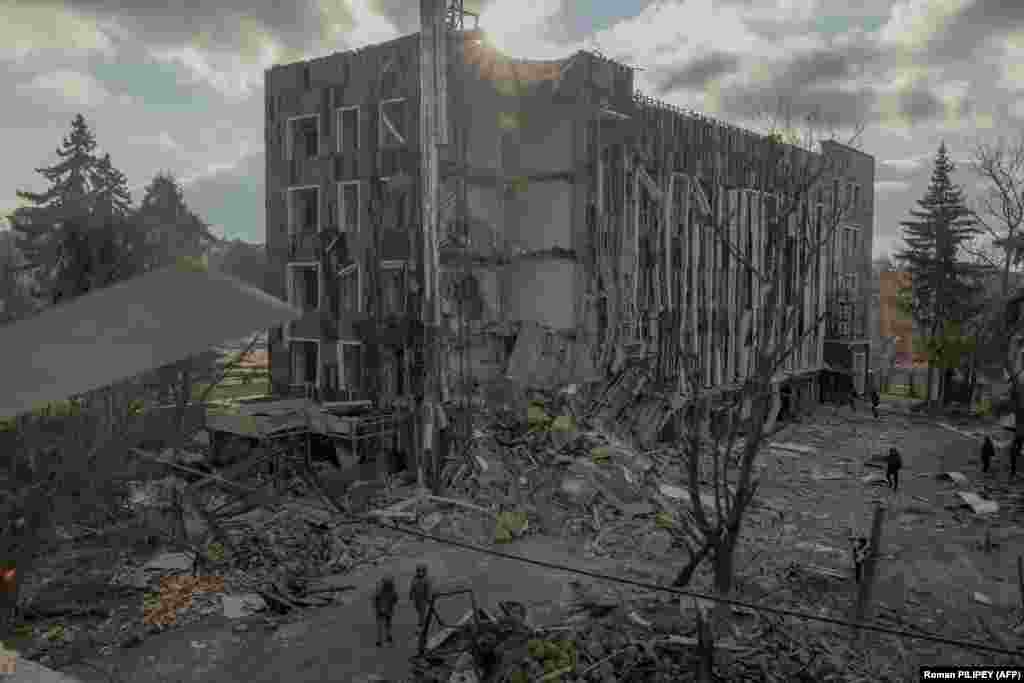 Ukrainian security officers and others check a heavily damaged building at the site of a missile attack in the city of Izyum in the Kharkiv region. 