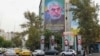 A woman walks past a billboard showing a portrait of Hamas leader Yahya Sinwar next to Palestine Square in Tehran.