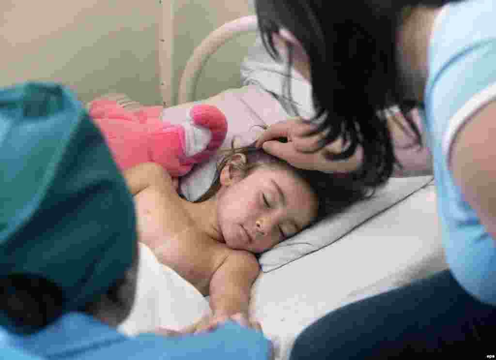 A mother touches her injured daughter&#39;s hair as she recovers at a hospital in Vladikavkaz, the regional capital of North Ossetia.