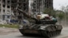 Pro-Russian troops drive a tank past a destroyed residential building in the town of Popasna in Ukraine's Luhansk region on May 26.