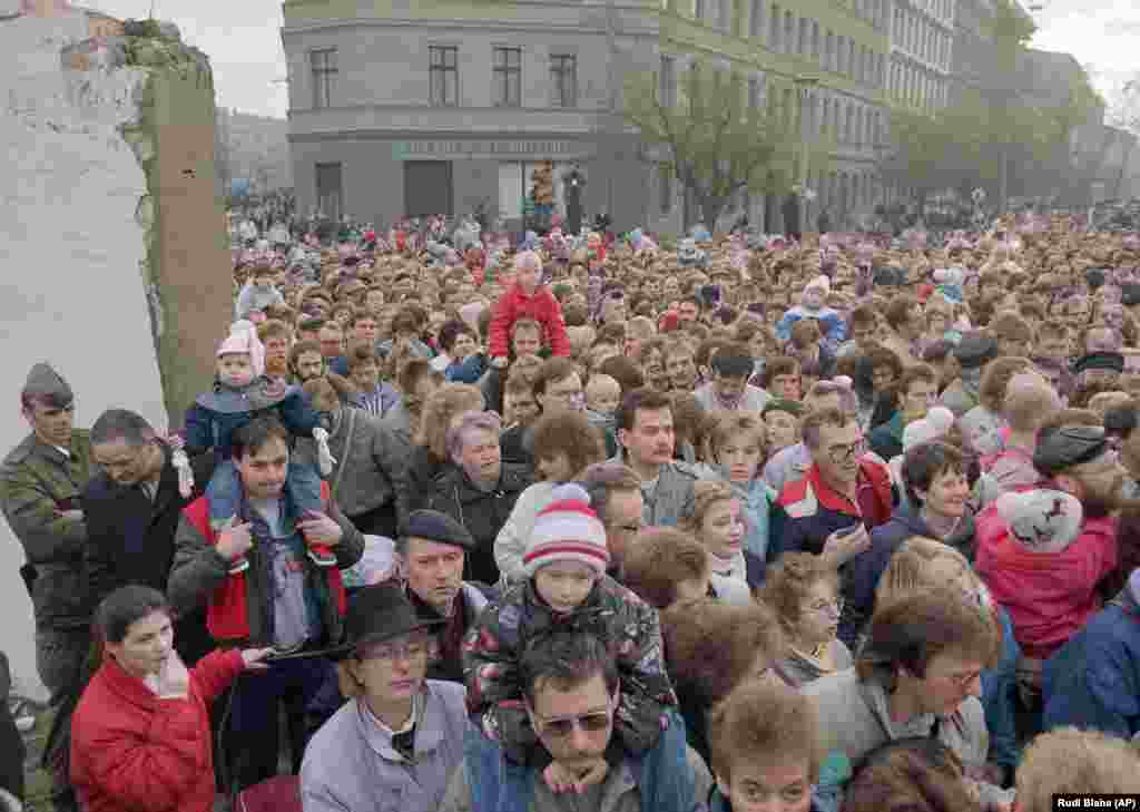 People stream through a breach in the wall on November 11 after East German soldiers were ordered to stand aside, effectively ending the physical divide between East and West Berlin.&nbsp;