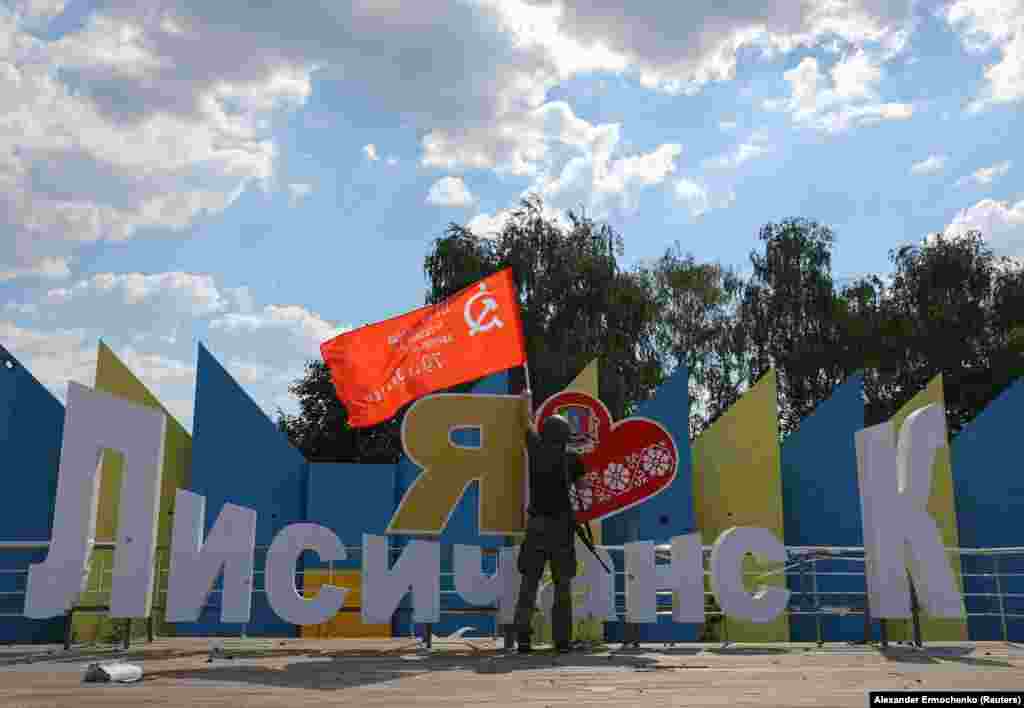 A Russian-backed separatist holds a Soviet-era flag, which was raised to mark the anniversary of the victory over Nazi Germany in World War II at the &quot;I love Lysychansk&quot; monument on July 4 after Ukrainian forces were forced to withdraw.