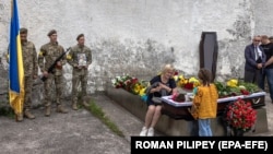 Oksana, the mother of Ukrainian Army soldier Yevhen Olefirenko, together with his daughter Dzvenyslava, mourn next to his body during a funeral ceremony in Kyiv on July 9.