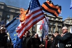 Seselj (right), surrounded by his supporters, holds a burning U.S. flag during an antigovernment rally in Belgrade on March 24.