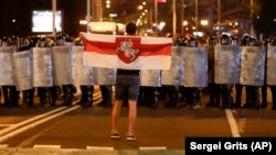 A protester holds a forbidden red-and-white Belarusian flag as he stands in front of a police line during a rally after the disputed Belarusian presidential election in Minsk in August 2020.