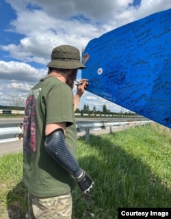 Shota Bitadze signs a regional welcome sign in Ukraine.