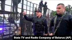 Belarusian President Alyaksandr Lukashenka, armed with a Kalashnikov-type rifle, greets riot-police officers near the Palace of Independence in Minsk amid massive opposition protests on August 23.