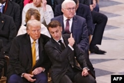 French President Emmanuel Macron (center) points toward his German counterpart Frank-Walter Steinmeier (right) as he talks with U.S. President-elect Donald Trump inside Notre-Dame Cathedral ahead of a ceremony to mark the re-opening of the landmark building in December.