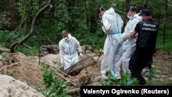 Forensic experts exhume a body of someone who, according to police, was killed by the Russian military in the Bucha district outside Kyiv in June 2022.