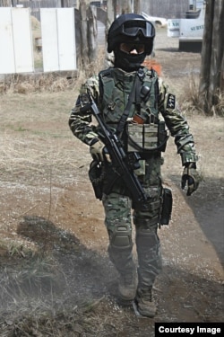 Hayato Sato dressed in a Russian special-forces outfit. Airsoft pellets can be seen littering the ground. The gun is a replica of the German-made Heckler & Koch submachine gun sometimes used by the FSB’s Alpha Group.