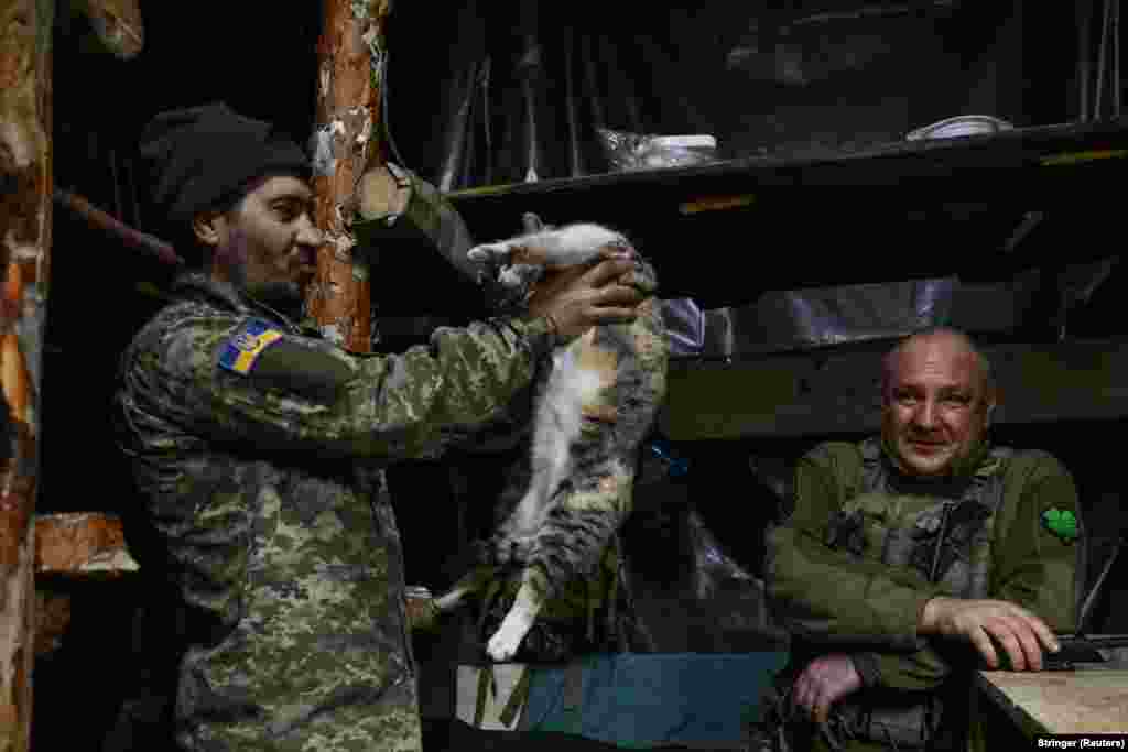  A Ukrainian soldier of the 110th Territorial Defence Brigade of the Ukrainian Armed Forces holds a cat inside a dugout at a position on a front line in the Zaporizhzhya region. &nbsp; 