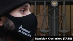 A man in a face covering with a message reading "There Is No Way To Ban Memorial" is seen outside Russia's Supreme Court on December 14.