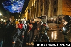 Protestors move toward riot police behind a makeshift barricade alongside the parliament building.