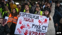 A Belgrade student hold a placard reading "Corruption kills, you have blood on your hands" as protesters gather outside the Supreme Public Prosecutor's Office on December 25 to demand accountability for the deadly rooftop collapse at the Novi Sad train station.