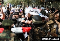 Taliban soldiers stand in front of protesters rallying for women's rights and against the Taliban in Kabul on September 7.