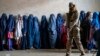 A Taliban fighter stands guard as women wait to receive food rations distributed by a humanitarian aid group in Kabul in May 2023. (file photo)