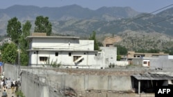 Pakistani police, reporters, and local residents gather outside the compound where Al-Qaeda leader Osama bin Laden hid out in Abbottabad on May 3.