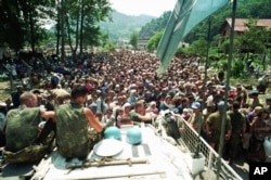 Dutch UN peacekeepers sit on top of an armored personnel carrier while Muslim refugees from Srebrenica gather in the village of Potocari, just north of Srebrenica, on July 13, 1995.