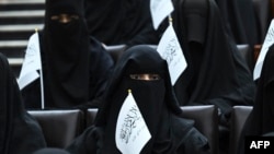 Veiled students hold Taliban flags as they listen to a speaker before a pro-Taliban rally at the Shaheed Rabbani Education University in Kabul.