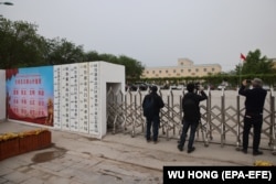 Foreign journalists take photos and video outside a location in China's Xinjiang region that was identified in early 2020 as a reeducation facility but which the Chinese government asserts is currently home to a veterans' affairs bureau and other government offices.