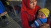 A Uyghur woman holds her baby in a night market in Hotan, in China's western Xinjiang region. (file photo)