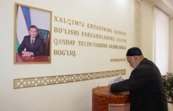 A man casts his ballot next to a portrait of Uzbek President Shavkat Mirziyoev during parliamentary elections in Tashkent on December 22.