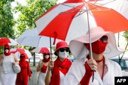 Belarusian women march down the street holding umbrellas in the colors of the former white-red-white flag of Belarus to show their solidarity with imprisoned protesters and opposition figures in Minsk on July 18.