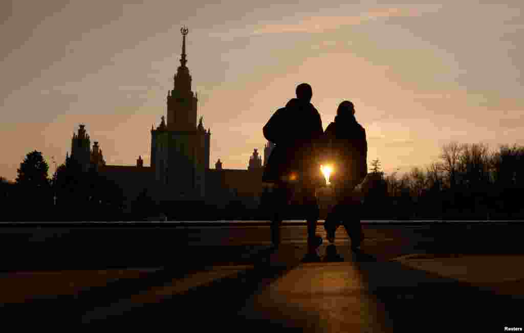 A couple runs across the road in front of Moscow State University in the Russian capital. 