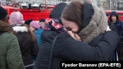 Two girls comfort each other as they cry near the site of a shopping-mall fire in the Siberian town of Kemerovo that left scores of people dead, many of them children. 